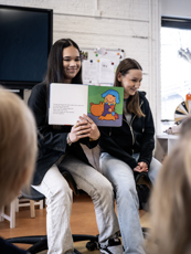 PW P1064884 Juli 2025 Twee studenten PW laten voorleesboekje zien aan de kinderen