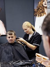 Studente barbier is haar aan het scheren tijdens de les