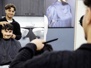 Student kijkt lachend via de spiegel naar de klant