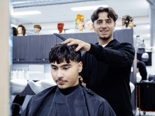 Student barbier aan het werk met een klant